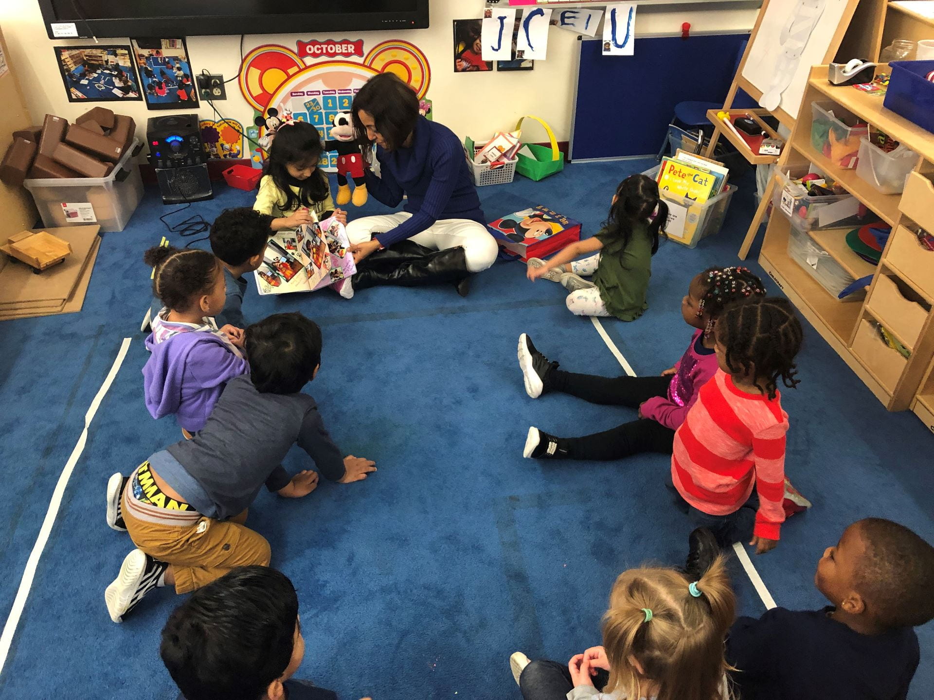 children and staff reading a book together on the rug