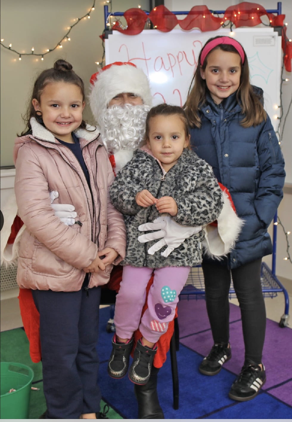 3 girls taking a picture with Santa Claus.