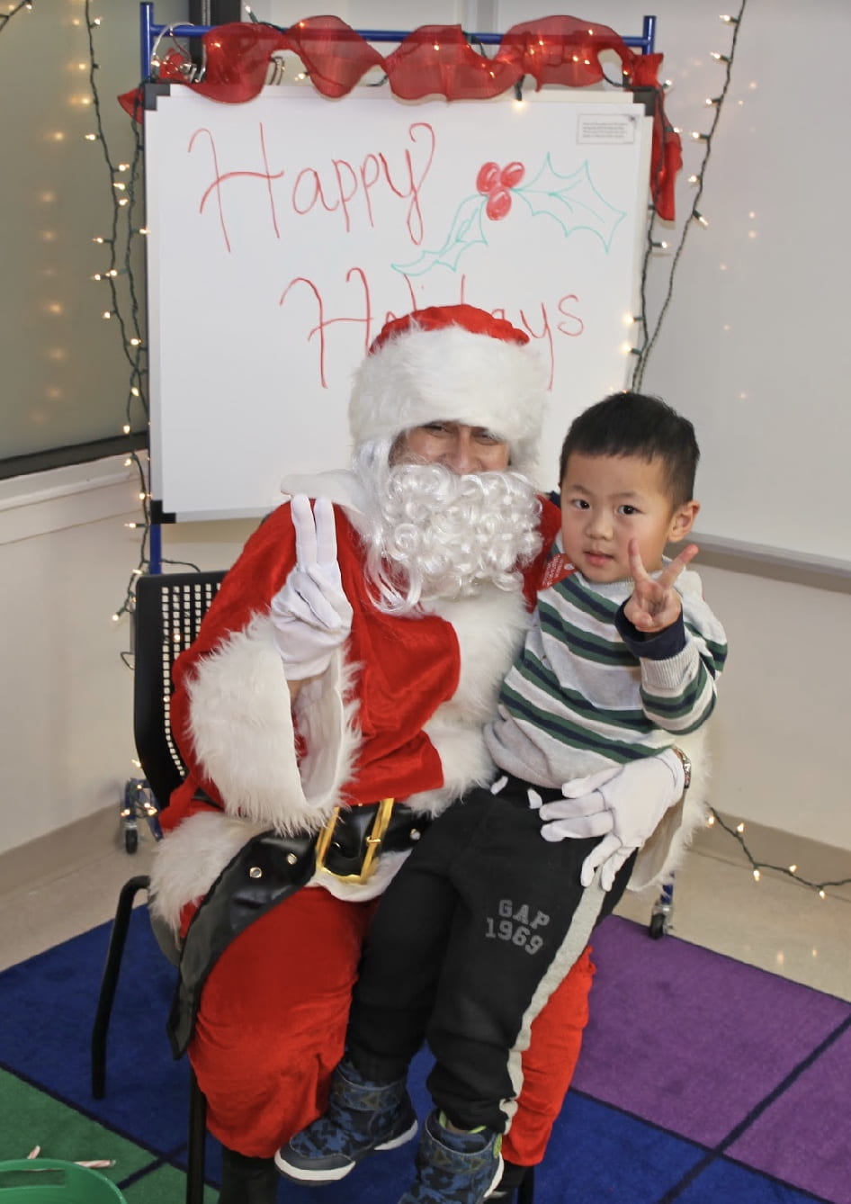 Student and Santa Claus making a peace sign with their fingers.