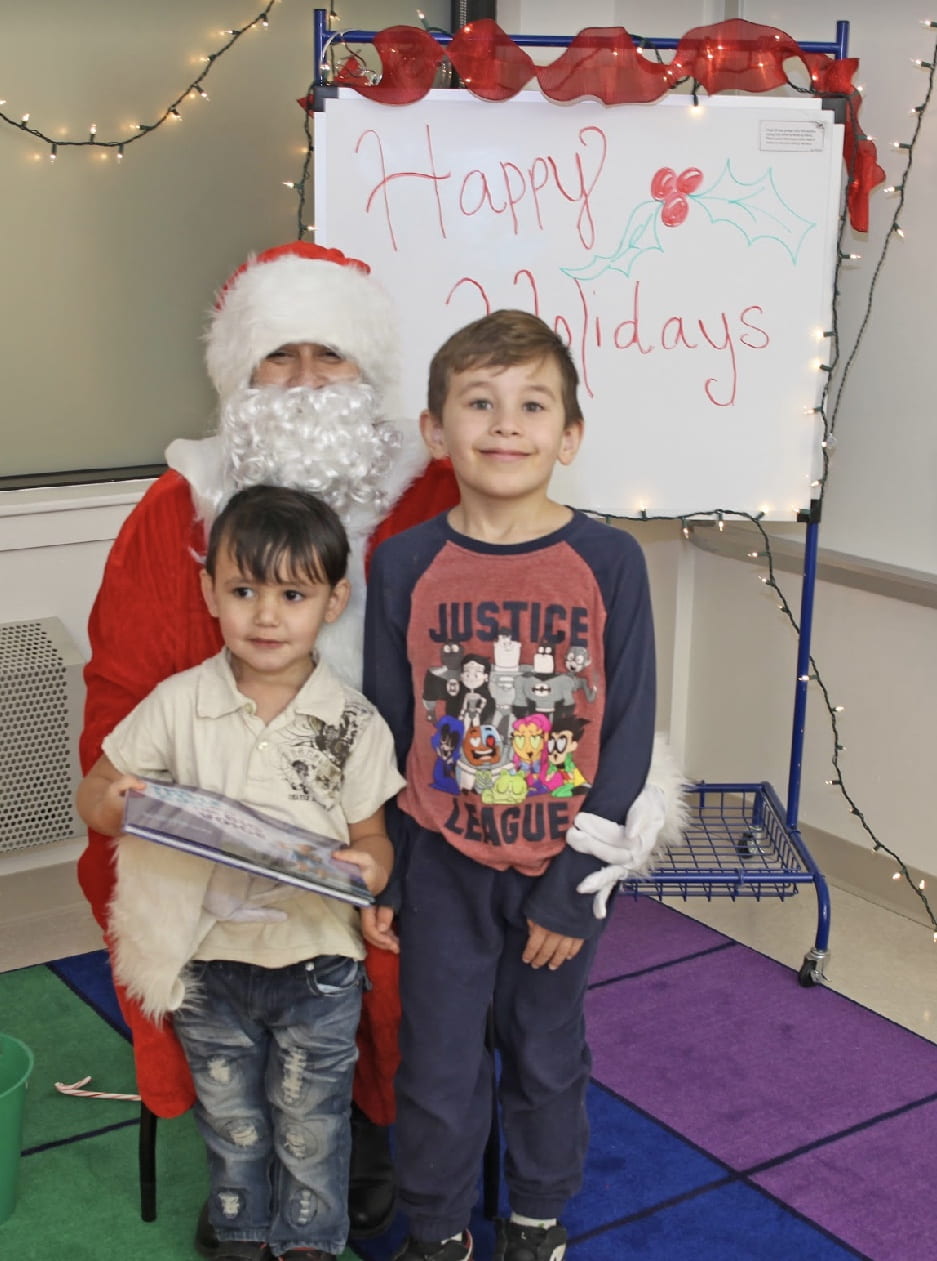 Two boys taking a picture with Santa Claus.