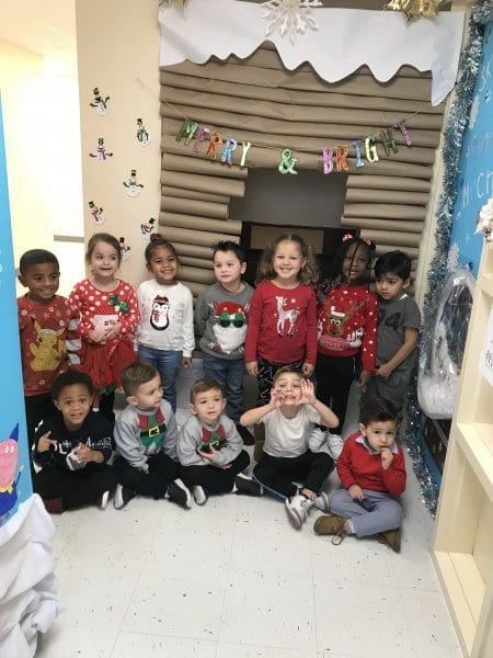 students posing for a picture in front of their classroom log cabin