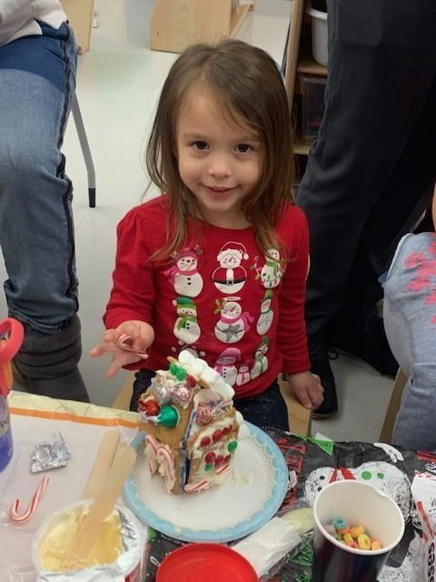 Student putting candy canes on her gingerbread house.