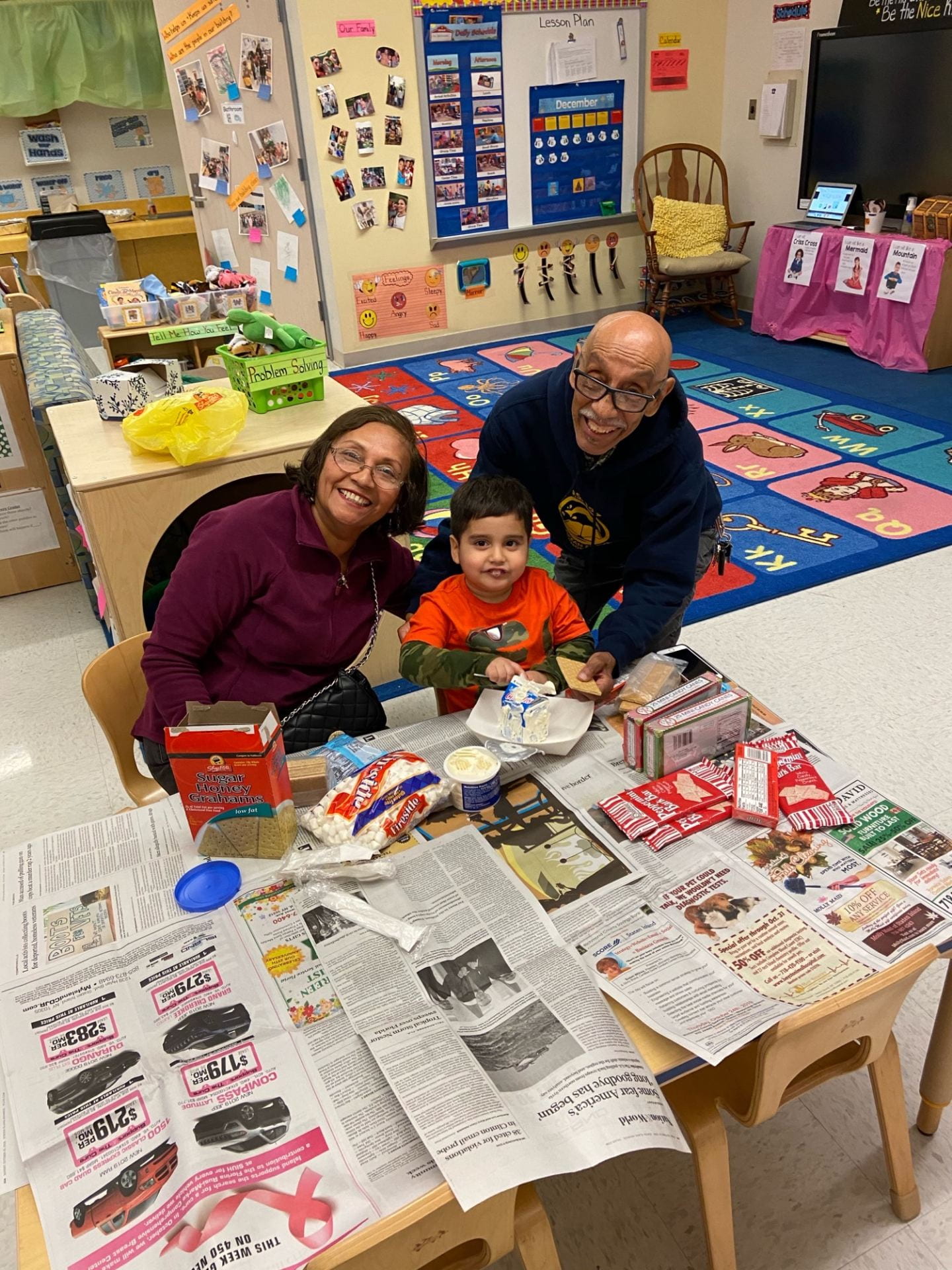 Student using white frosting to build his gingerbread house. Student using white frosting to build his gingerbread house.