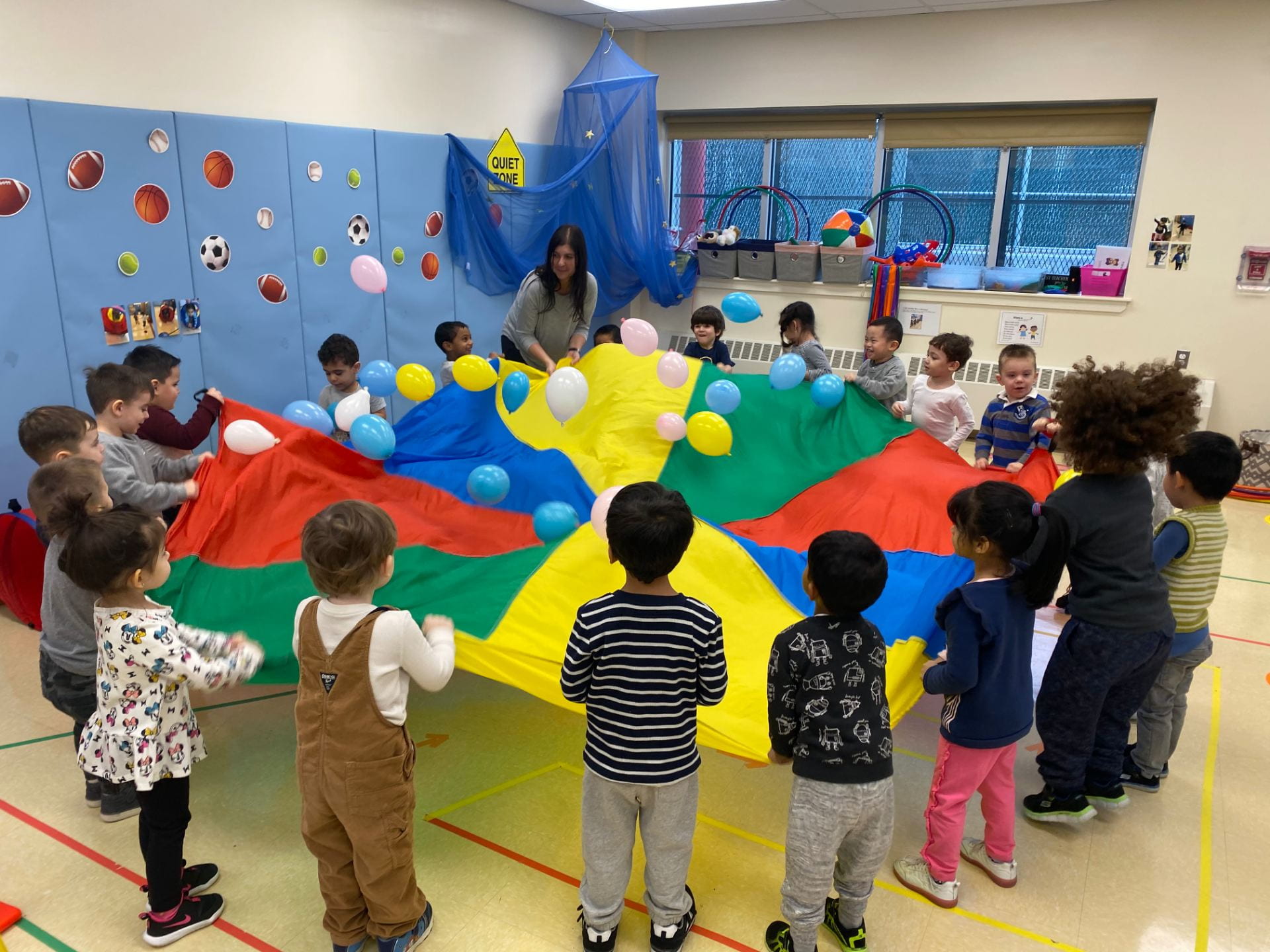 students shaking balloons on a parachute