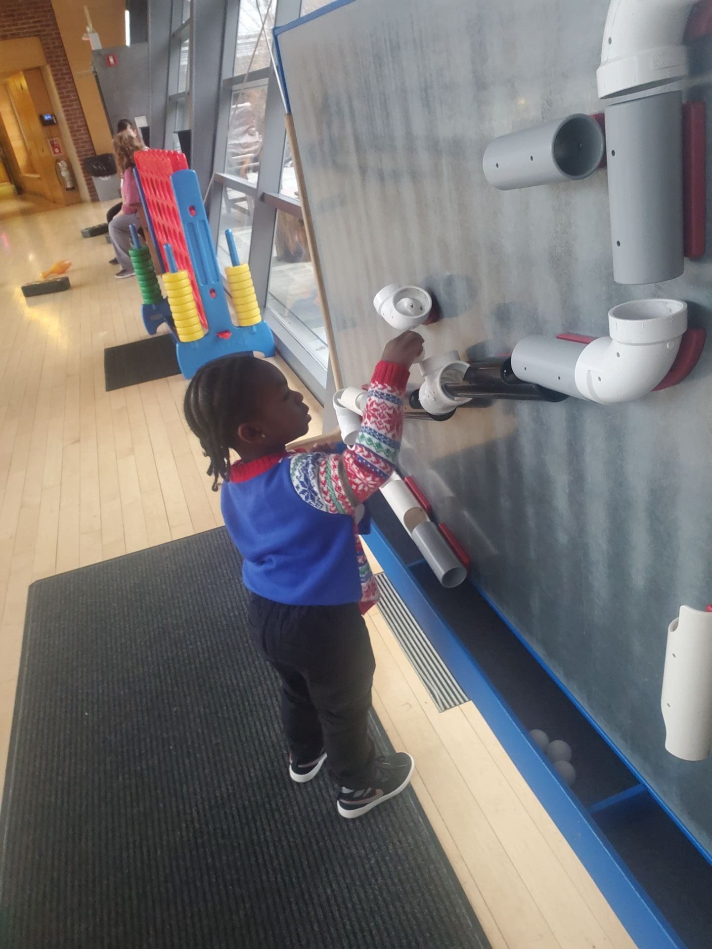 child putting a ball in PVC pipes at the children's museum child putting a ball in PVC pipes at the children's museum