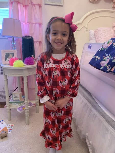 child wearing pj's standing next to her bed