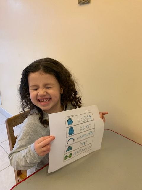 child showing excitement and holding up her completed assignment